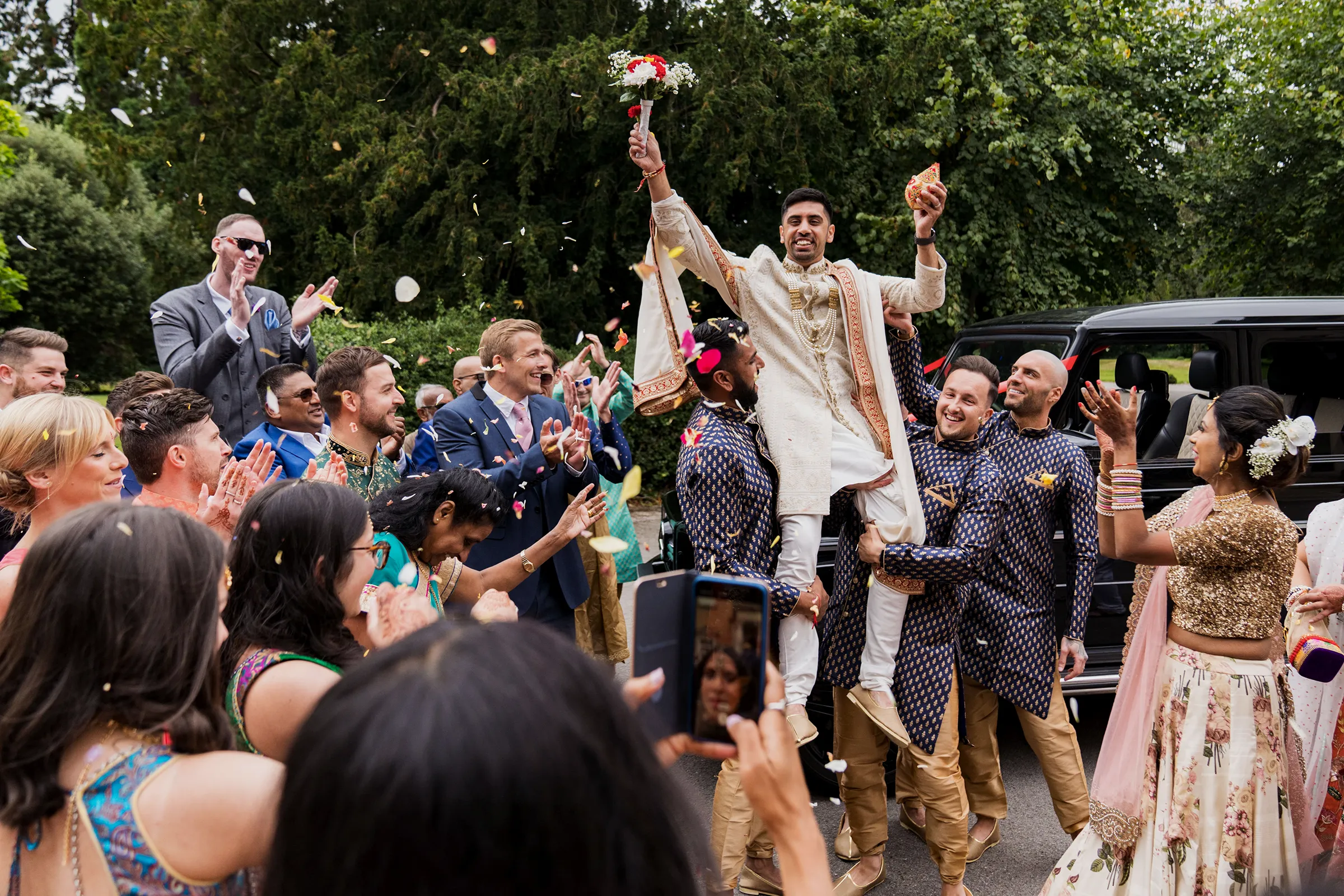 groom lifted by friends for his indian wedding baraat