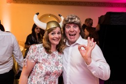 two wedding guests pose for a photo wearing a mullet wig and viking hat