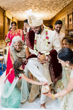 wedding guests take the shoes of the groom as he approaches the mandap