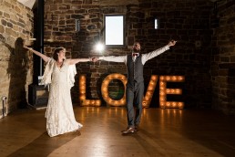 a first dance in front of lights spelling out LOVE