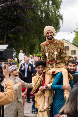 Indian groom is carried by two men into his wedding at Ribby Hall