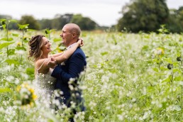 bride and groom laughing in a field of sunflowers
