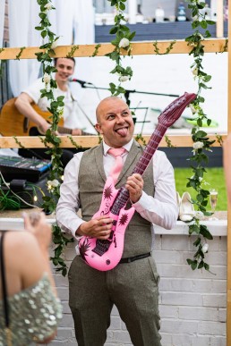 wedding guest plays a pink inflatable guitar at a wedding reception