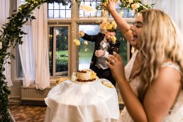 groom throws cake at his bride on their wedding day
