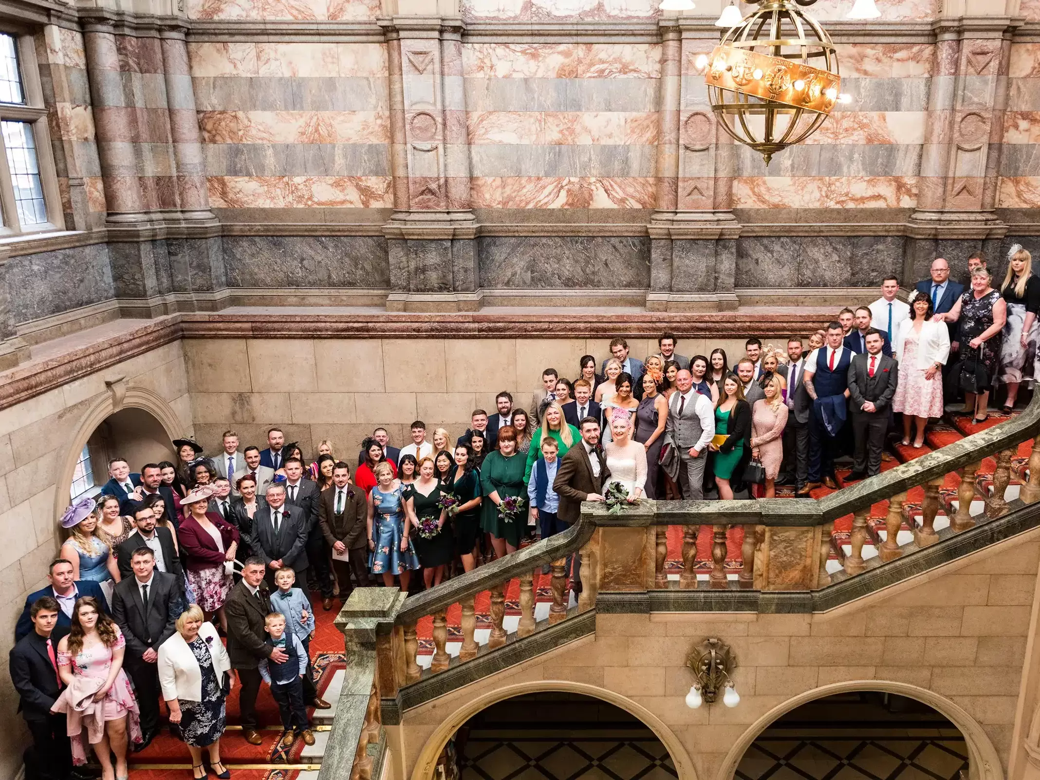 Full wedding guest group photograph on the grand staircase at Sheffield Town Hall, shot from the balcony opposite