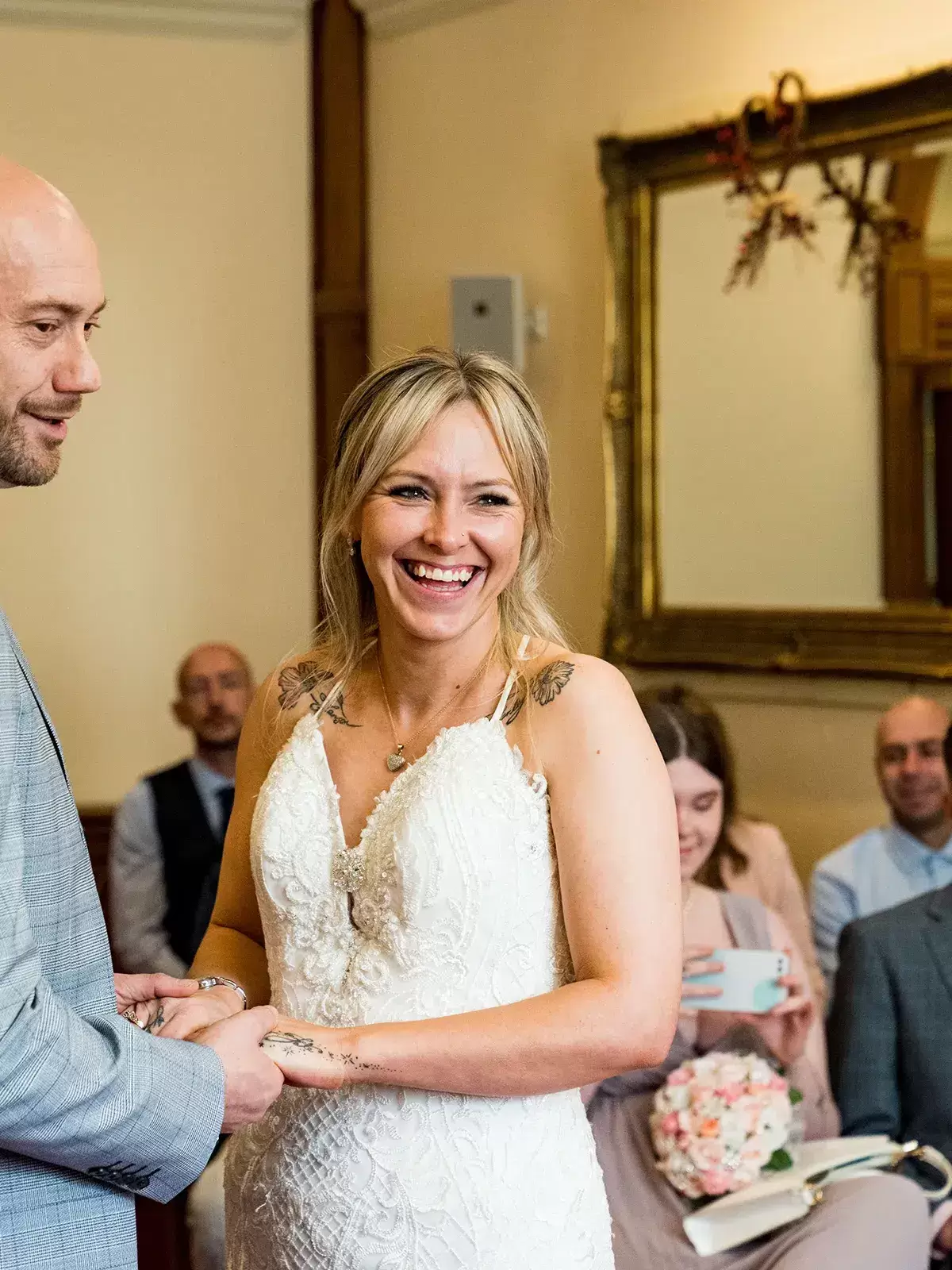 Couple holding hands during vows in the Arundel Room at Sheffield Town Hall, bride laughing as groom stumbles over his words