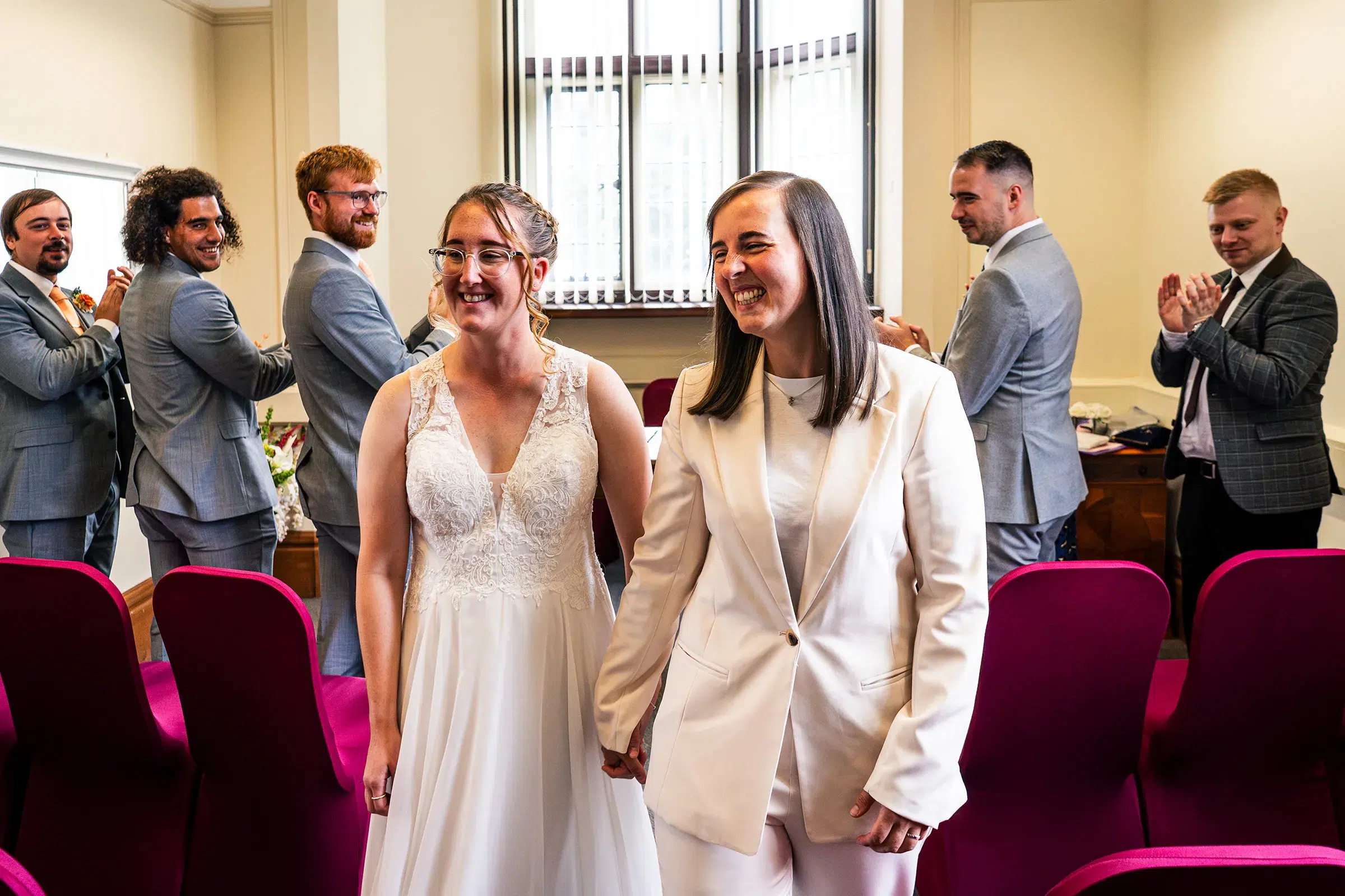 Two brides departing the Loxley Room at Sheffield Town Hall with guests after their wedding ceremony
