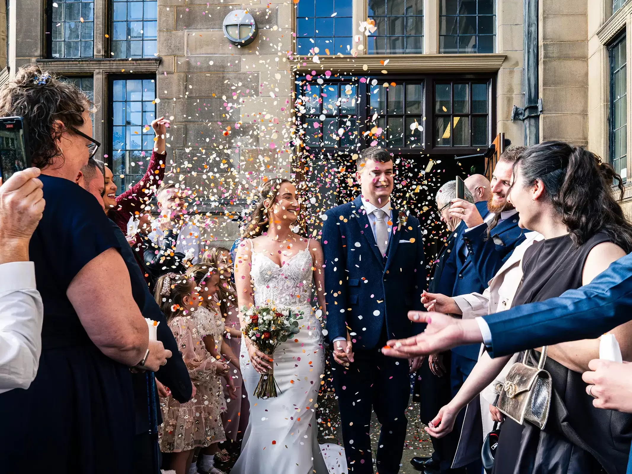 Bride and groom walking down the entrance ramp at Sheffield Town Hall as guests throw confetti